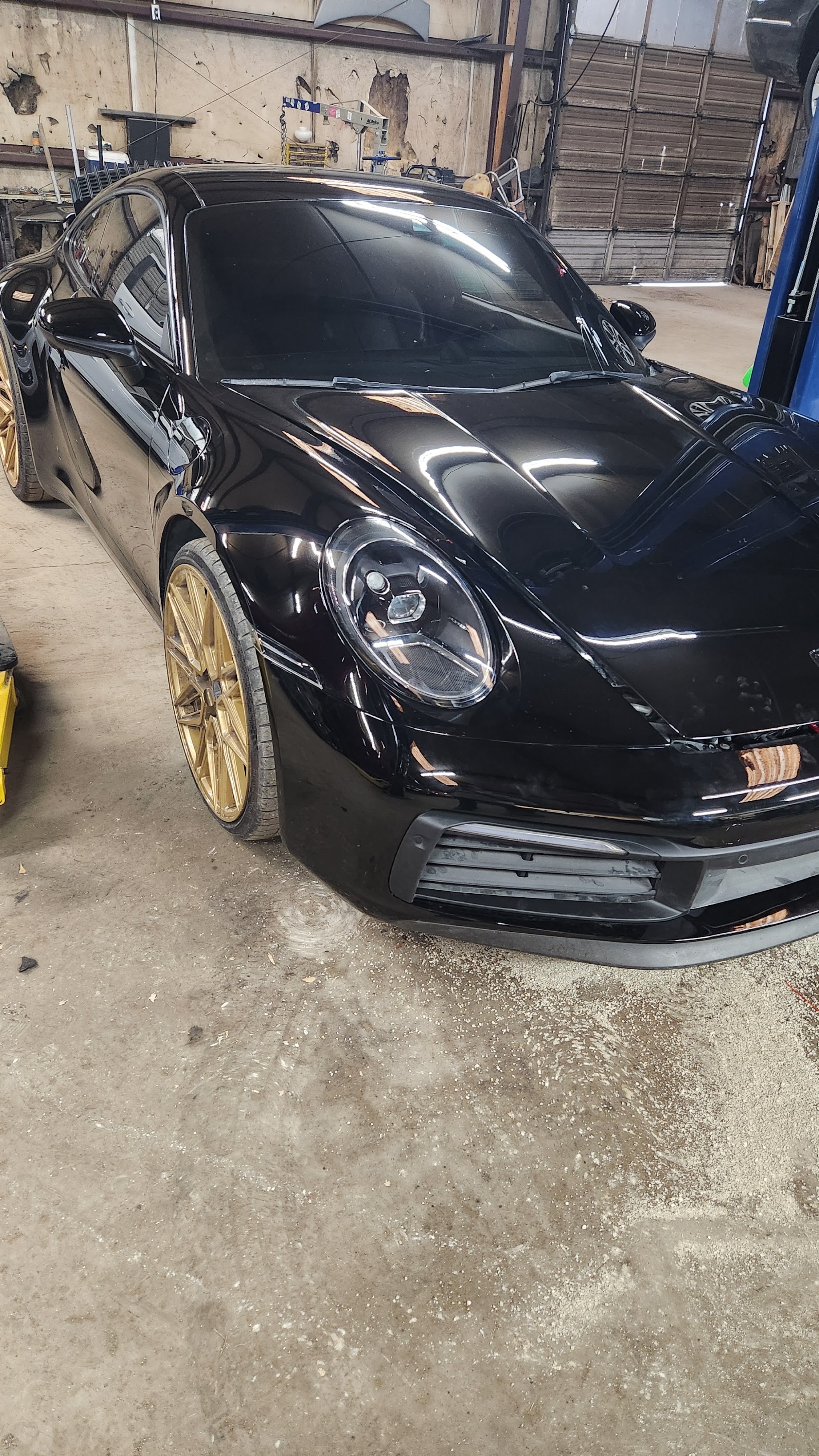 A black Porsche 911 with gold wheels in our shop